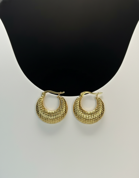 Gold hoop earrings on a mannequin bust with a plain background